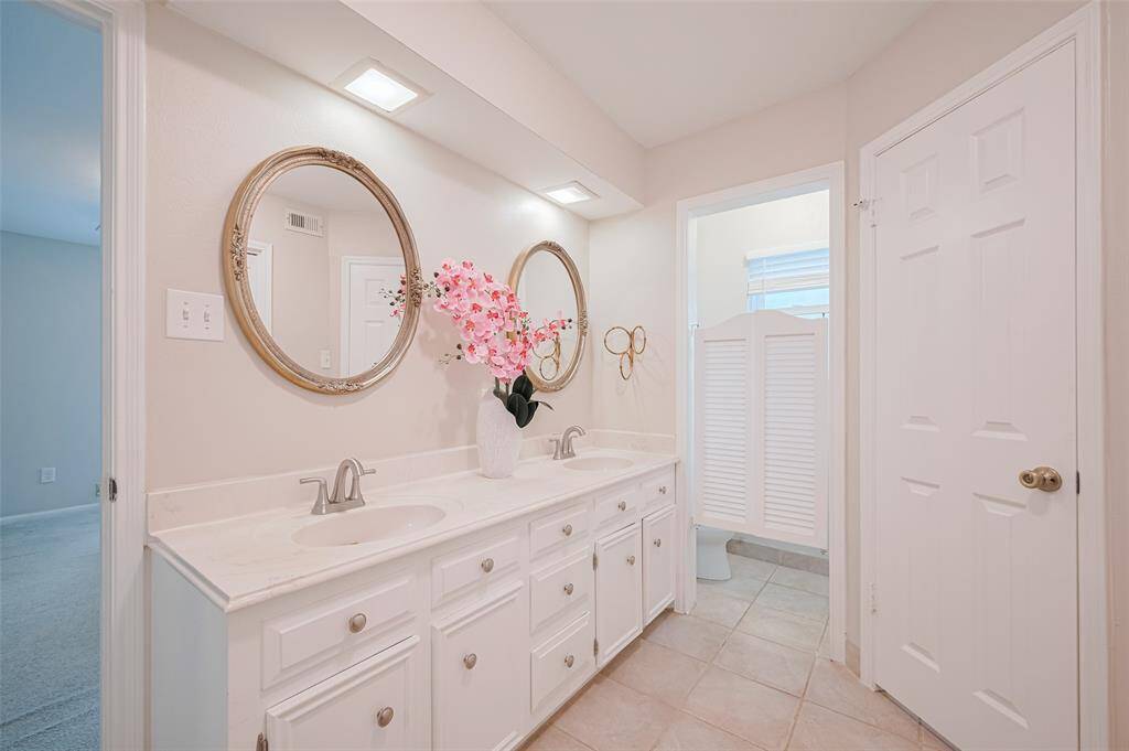 The primary bathroom showcases double sinks and includes distinct doors for both the bathtub and the WC, along with separate his and hers closets.