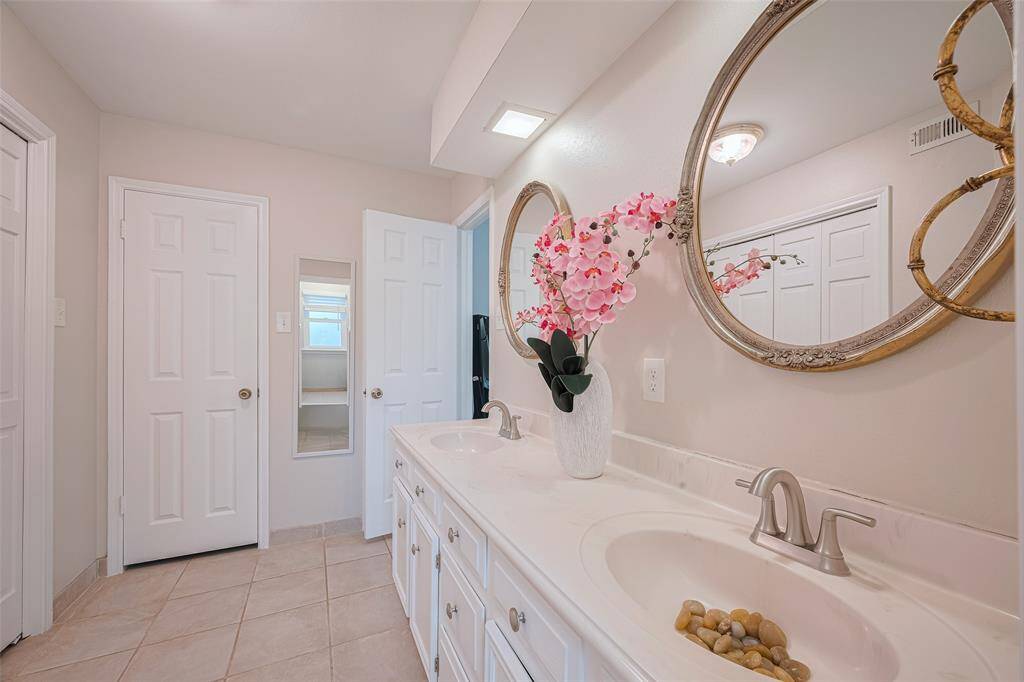 Another view of the primary bathroom showcasing double sinks.