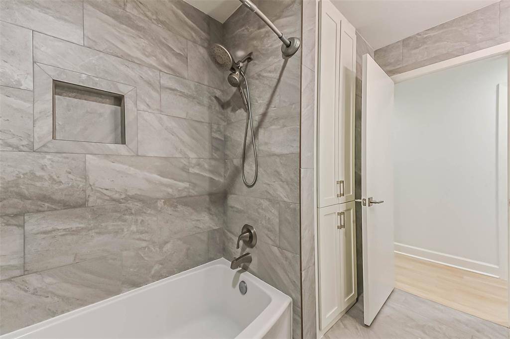 The secondary bathroom is accessible from the hallway and serves the seccondary bedrooms. The bathtub features an additional hand held shower head.