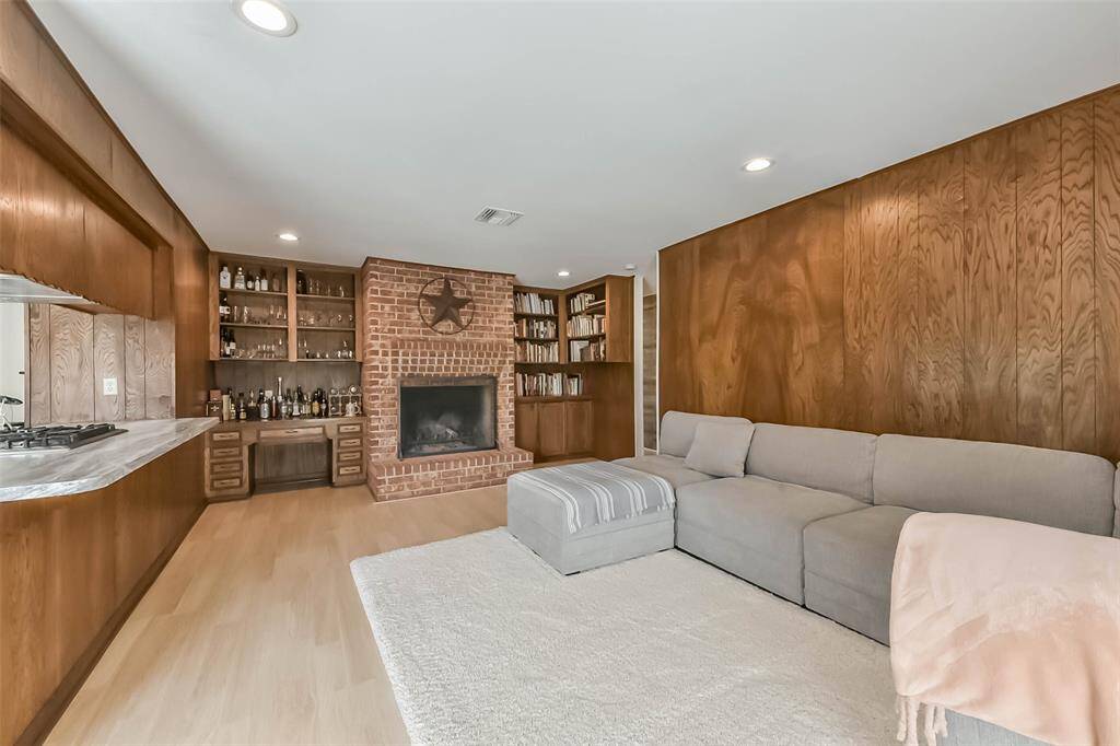 The rustic wood burning fireplace, surrounded by built-in shelves, conveys an almost country-like Texan feeling.