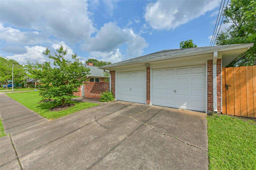 The double car garage is perpendicularly located to the house and has additional parking space in front of it. On the left hand side you see the white gate leading to the vegetable garden, the wooden door on the right hand side gives access to the large backyard.