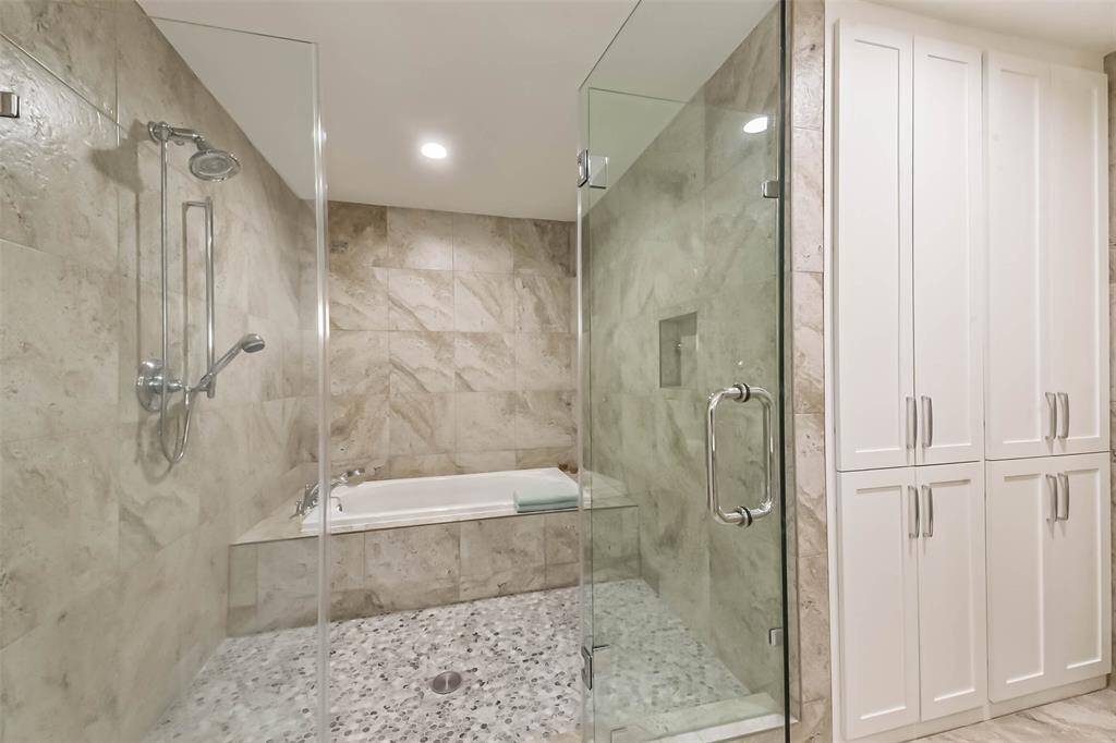 Indulge in the luxury of the spa area featuring an oversized shower and bathtub. Frameless double glass doors and a mosaic floor create a sleek and modern appearance. Built-in linen closets provide an abundance of storage.