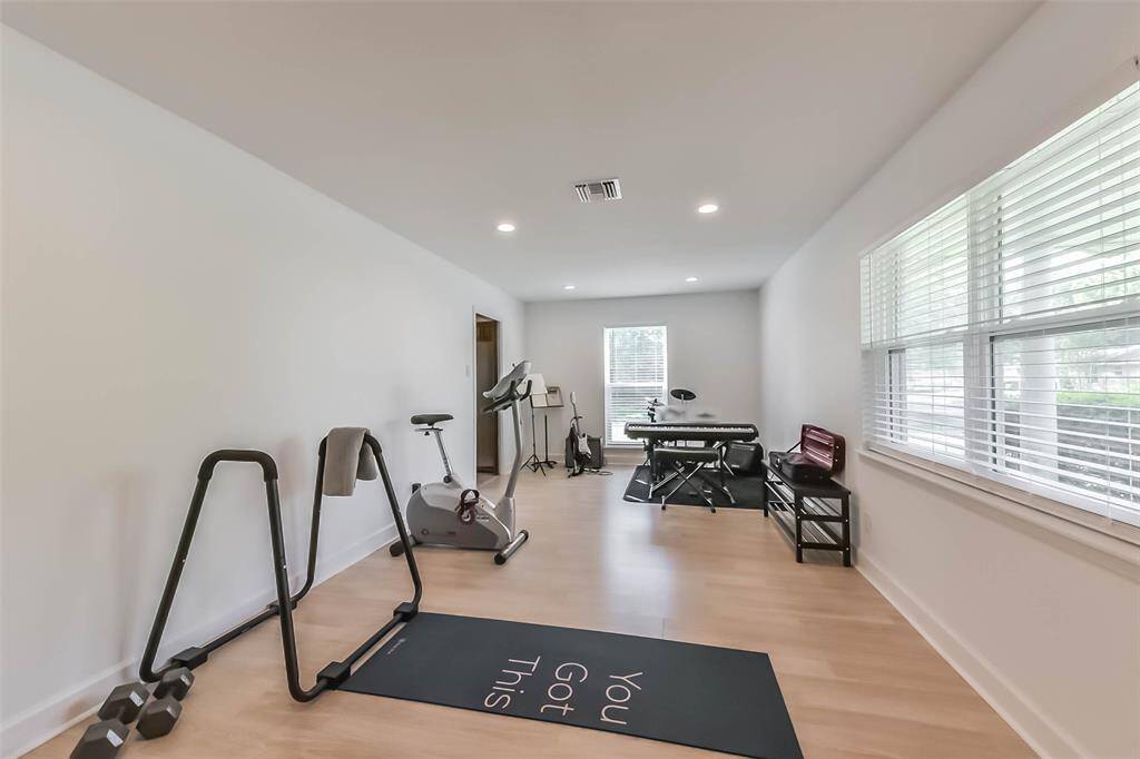 The large living room next to the entrance is currently converted to a music studio doubling also as a gym. The light color of the laminate floor as well as recessed LED lighting add to the sleek and modern feeling of the room. It can easily be repurposed to serve as a living room again.
