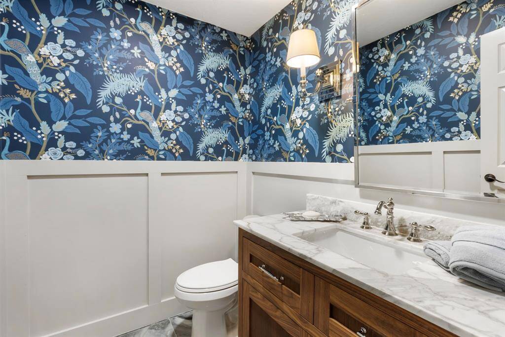 Half bath by front entry and office with solid walnut cabinets and natural marble countertop.