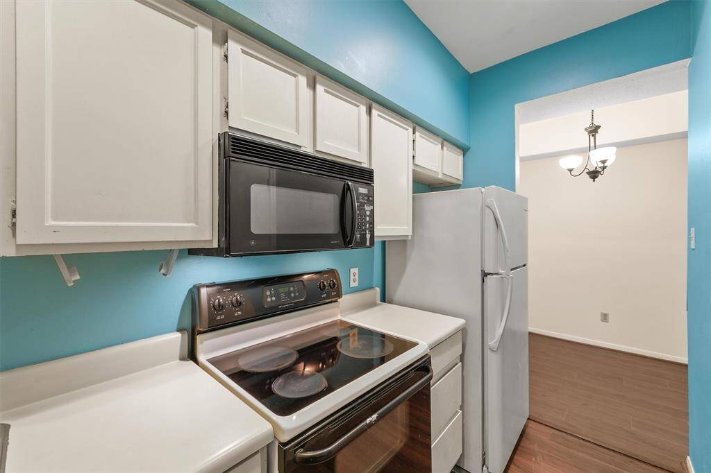 Cozy galley kitchen with crisp white cabinets and easy access to the dining area.
