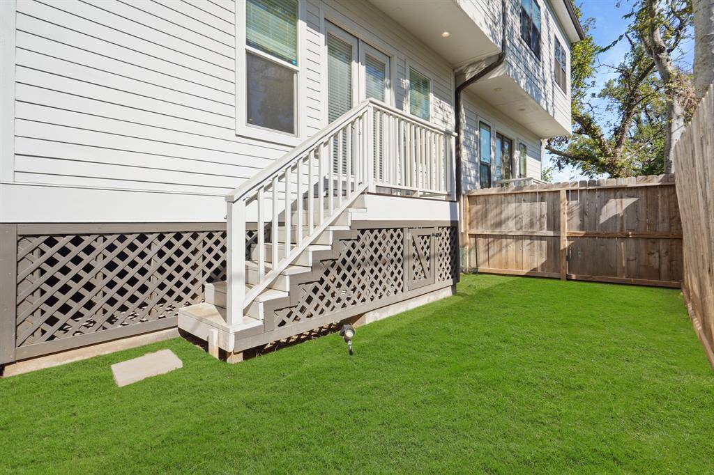 Back patio with stairs that lead to fully fenced lawn and side yard