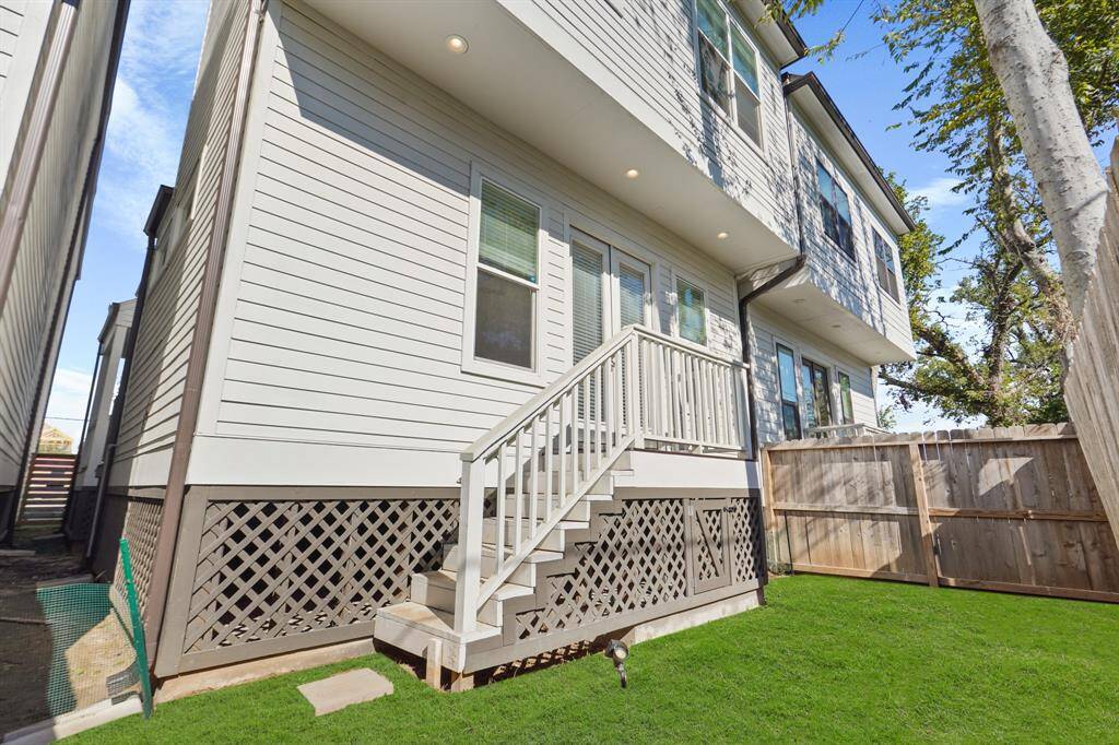Back patio with stairs that lead to fully fenced lawn and side yard