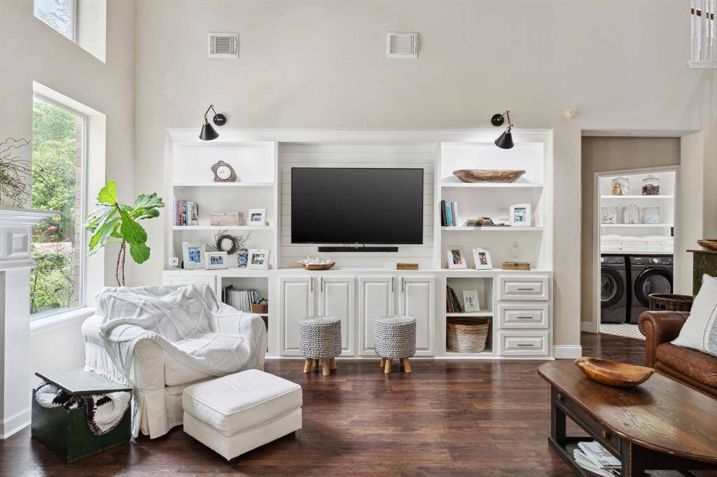 Living room features beautiful flooring, high ceilings, built-in shelving, and large windows.