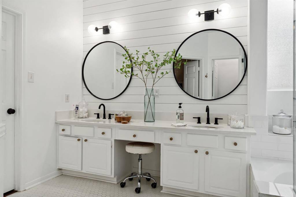 The primary bathroom has tile floors, dual sinks, and a vanity area.