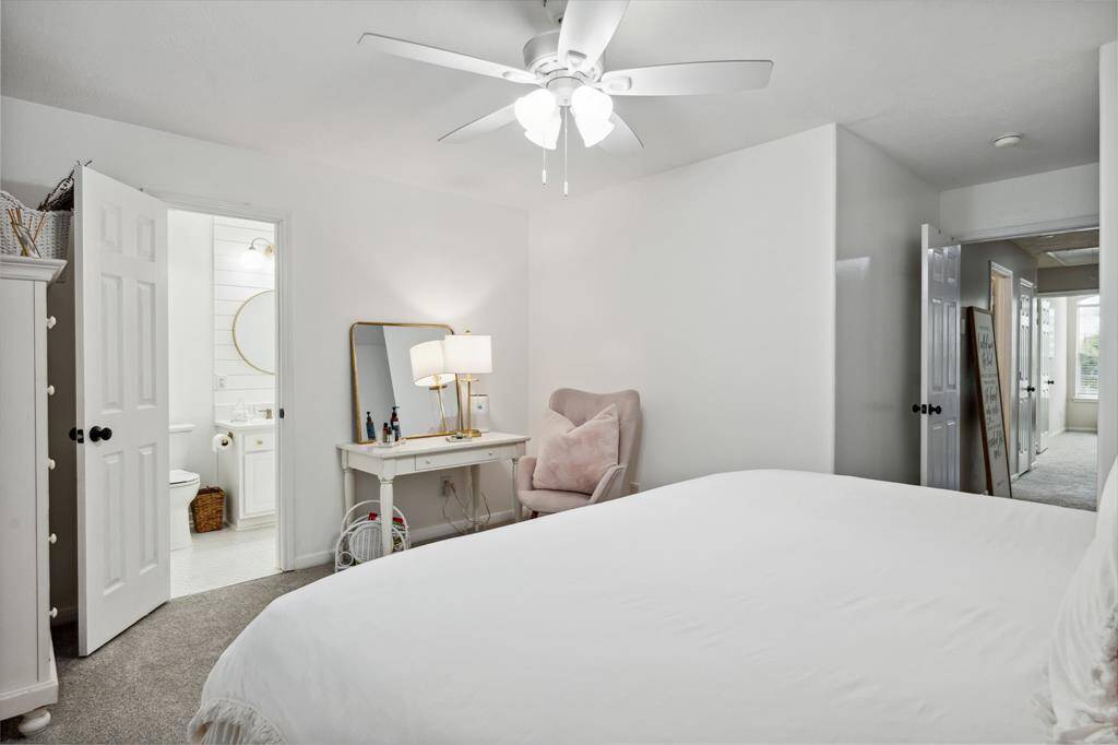 Secondary bedroom features awindow, ceiling fan, plush carpet, and en-suite bathroom.