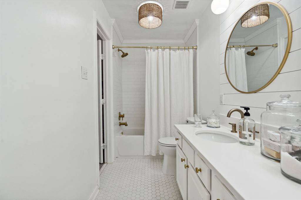 The en-suite secondary bathroom is a Jack and Jill bathroom with tile floors, dual sinks, and tub and shower combo with tile surround.