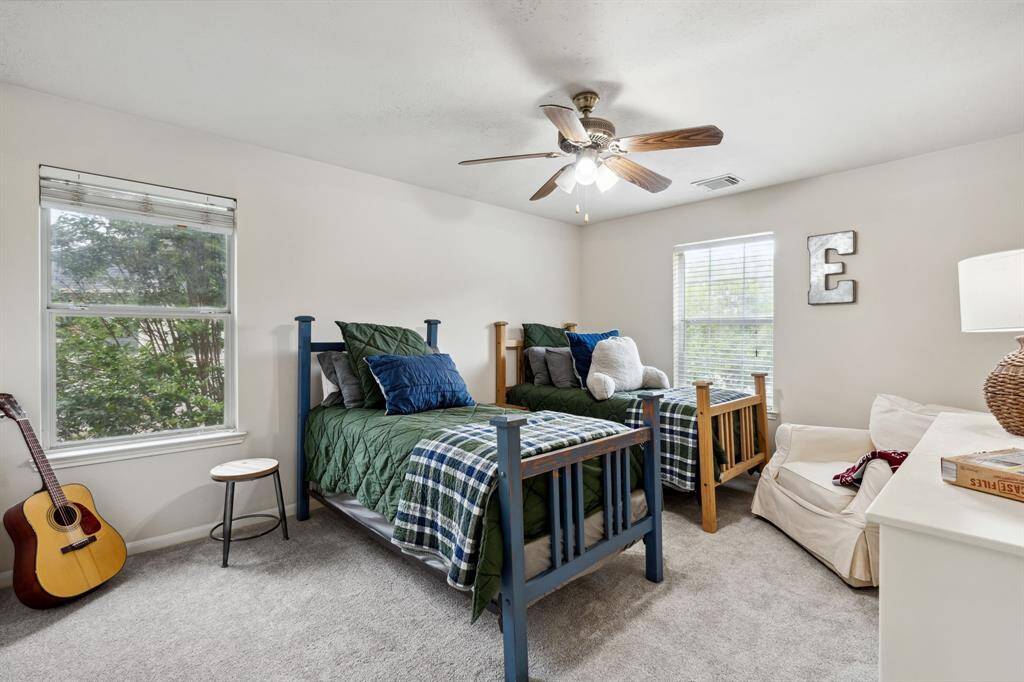 Fourth bedroom features windows, ceiling fan, and plush carpet.