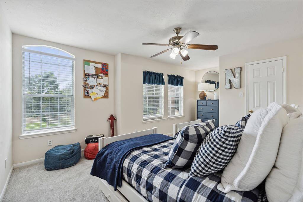 Fifth bedroom features windows, ceiling fan, and plush carpet.