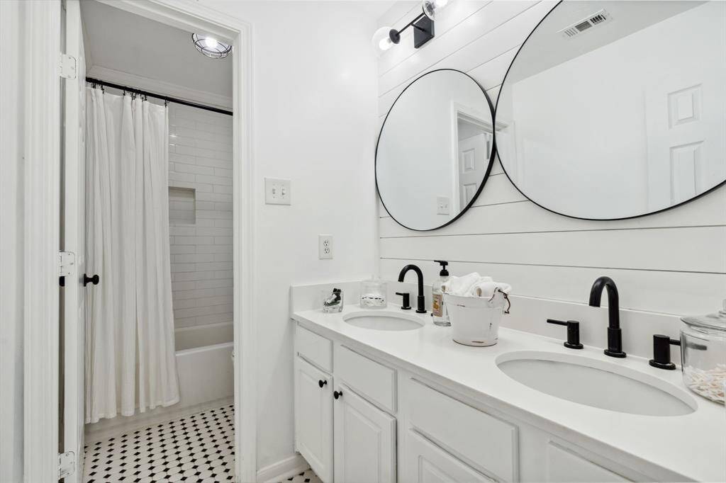 Third bathroom features tile floors, dual sinks, and tub and shower combo with tile surround.