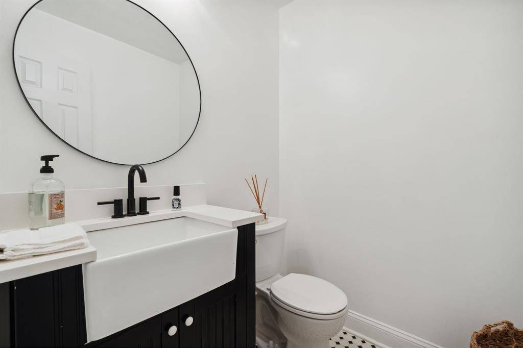 The half bathroom features tile floors and a modern farmhouse sink.