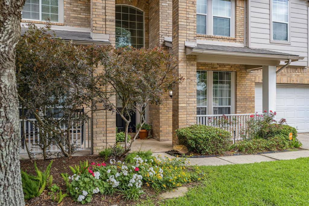 Approaching the front door is the covered front porch, brick elevation, and lovely landscaping.