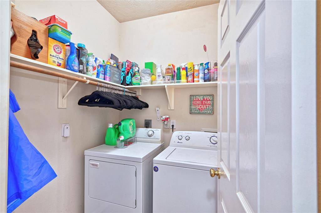 Walk in laundry room with a washer and dryer. Shelving above provides ample storage for cleaning supplies and other household items.
