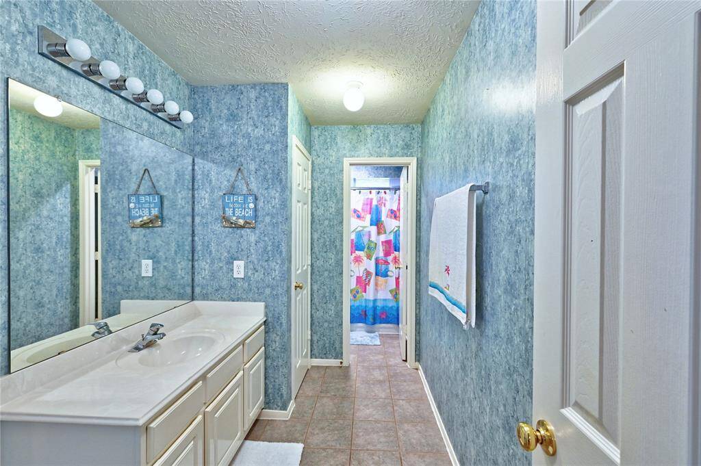The second bathroom on the second floor offers privacy for toilet area. Single-sink vanity with ample counter space, a large mirror with bright lighting, linen storage closet.