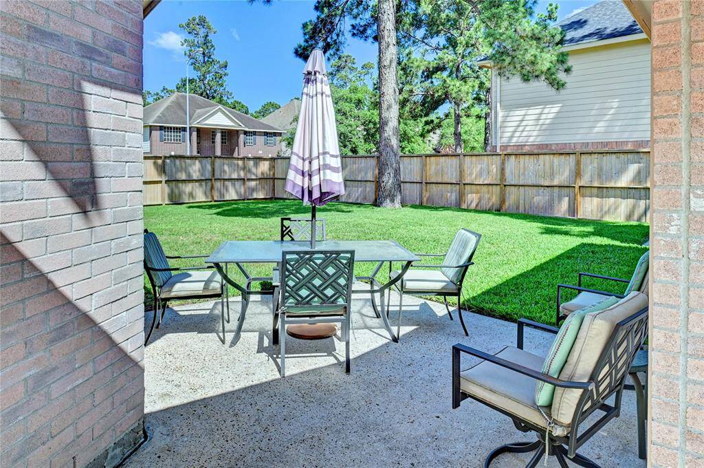 This photo showcases a charming backyard patio, surrounded by a well-maintained lawn and privacy fence.  Large corner lot is ideal for outdoor relaxation and entertaining.