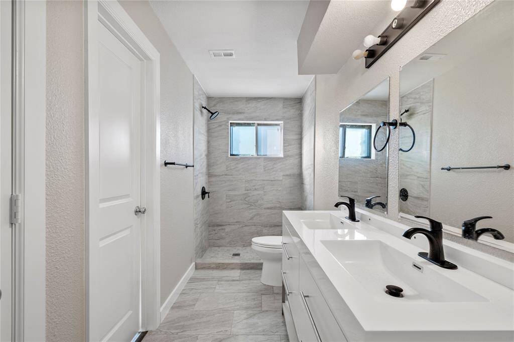 The primary bedroom features updated cabinets, new mirrors, modern black hardware, and fresh tiling — combining style and functionality in one beautifully updated space.