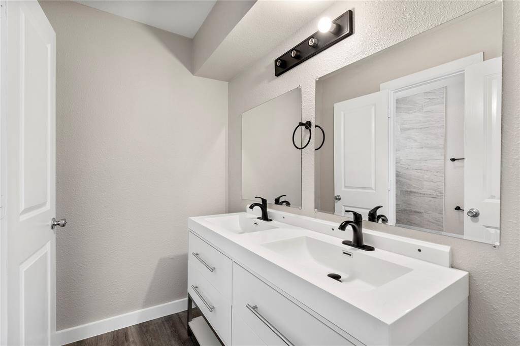 The upstairs secondary bedroom also features updated elements, including new cabinets, sleek black hardware, new mirrors, and fresh tiling — blending modern style and functionality.
