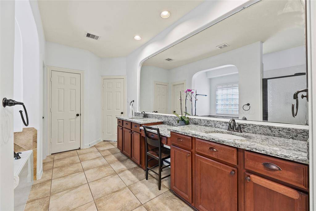 One seemingly endless mirror runs the length of the granite countertops in the primary en suite.
