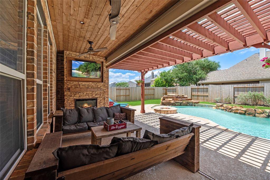 This covered outdoor patio offers year-round comfort with ceiling fans, recessed lighting, and a cozy fireplace. A TV mount above the fireplace makes it perfect for entertaining or relaxing outdoors in style.