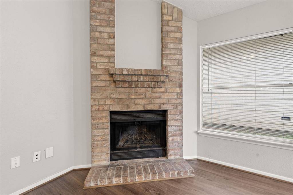The corner fireplace features a floor-to-ceiling brick surround and a sturdy brick mantel, adding warmth, charm, and a perfect spot to display décor.
