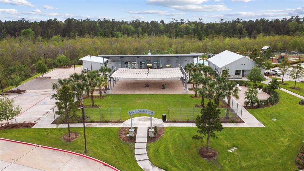 This photo showcases a community clubhouse surrounded by lush greenery, featuring a modern building with outdoor seating, a pool area, and well-maintained landscaping. Ideal for gatherings and relaxation.