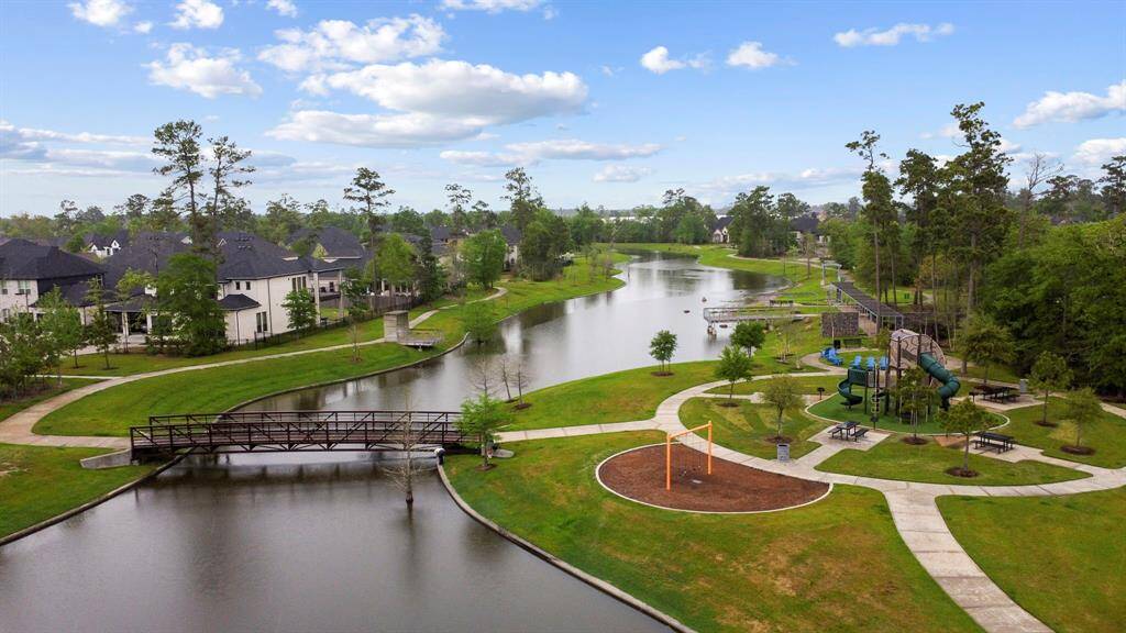 This photo showcases a serene residential area with a picturesque waterway, lush greenery, and a pedestrian bridge. Nearby, a well-maintained park features a playground and picnic area, offering a family-friendly environment and a tranquil setting for outdoor activities.