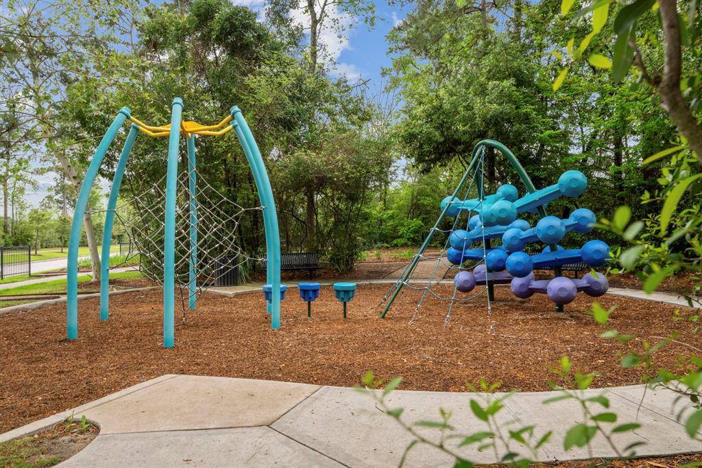 This photo shows a vibrant playground area nestled in a wooded setting, featuring unique climbing structures and surrounded by lush greenery, perfect for family-friendly activities.