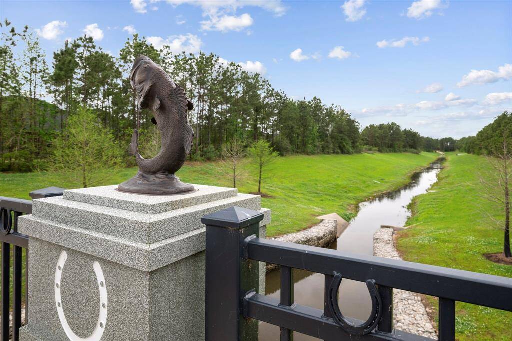 This photo showcases a scenic view from a bridge with a decorative fish sculpture and a peaceful waterway lined with lush greenery, offering a serene natural ambiance.