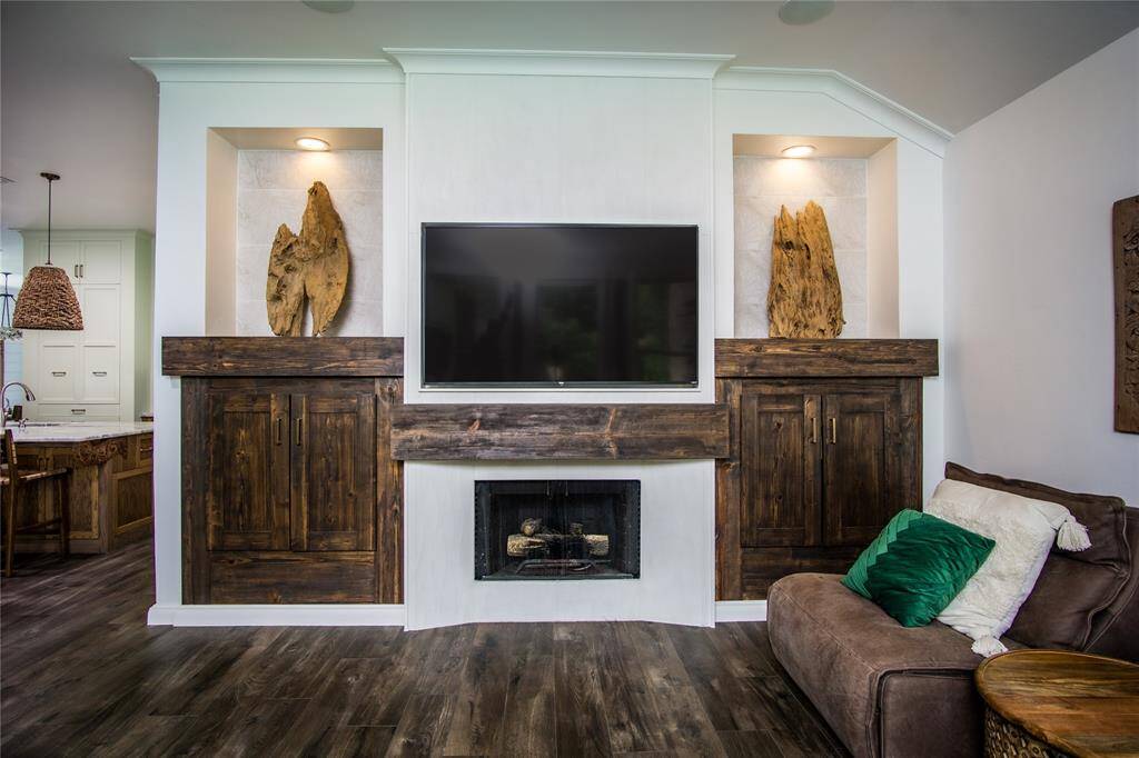 Notice the attractive wood trim used in this home. Gas fireplace surround was redone to incorporate a textured white tile surround, wood mantel & a nook to mount a TV flush with the wall. Cabinets on either side of the fireplace are great for storage. Beautiful tile backed niches with lighting.