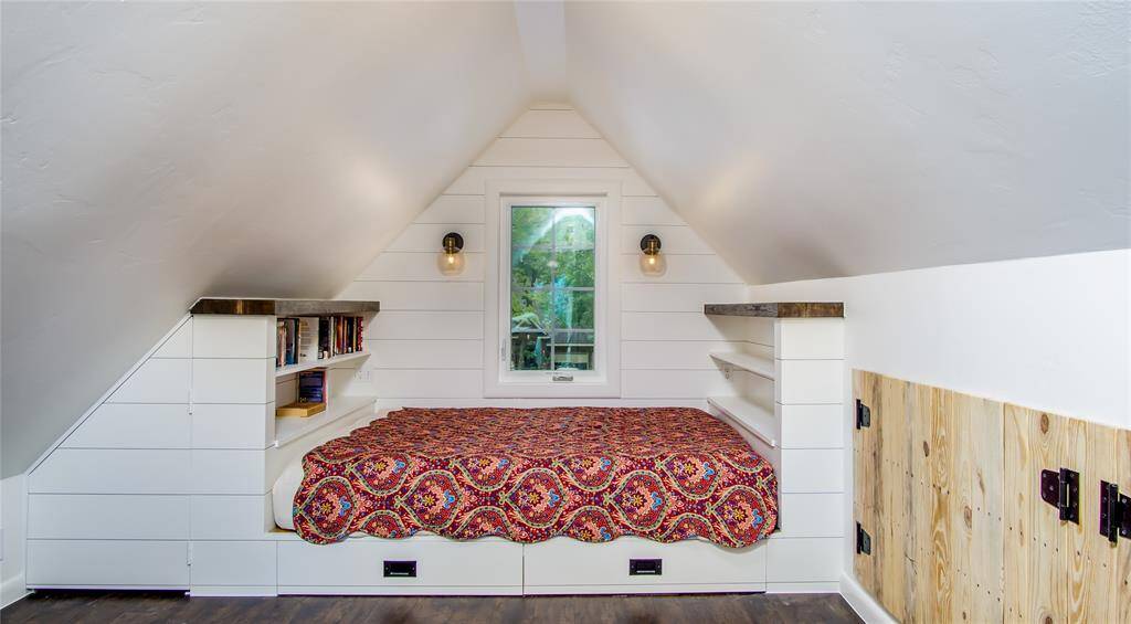 One view of the bonus room or 4th bedroom located upstairs. Built-in queen sized bed with book shelves & wood shiplap panels for beautiful design. Vinyl plank flooring in this room. Built in storage areas on both sides of the room.