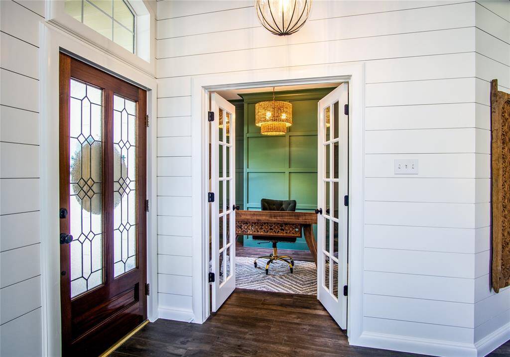 To the left of the entry way are beautiful, French doors leading into the office / study. The chandelier provides lighting with style.