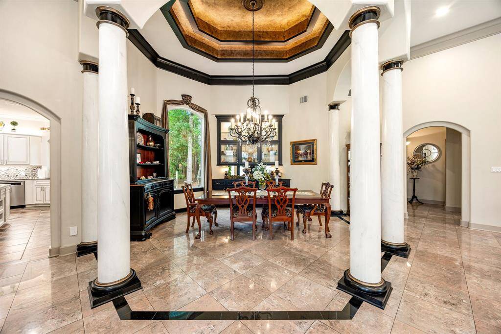 The formal dining room features elegant pillars and a beautifully detailed tray ceiling