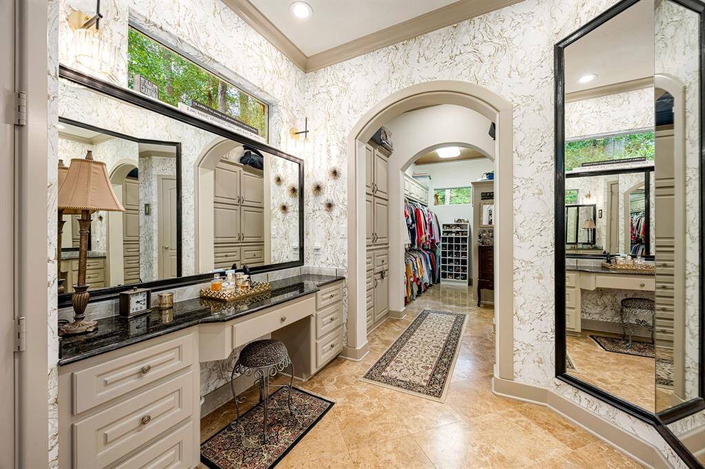The primary bathroom features a dedicated makeup vanity with built-in cabinetry and an elegant arched entry leading to a spacious walk-in closet