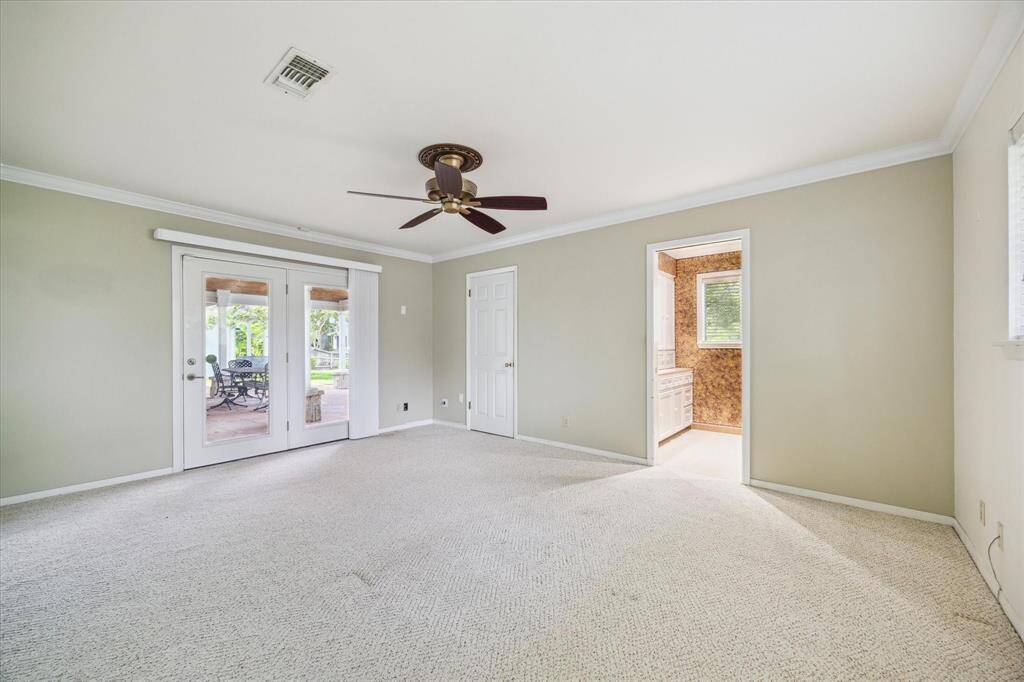 The primary bedroom has French doors that open to a covered patio and offers a relaxing view of the lake.