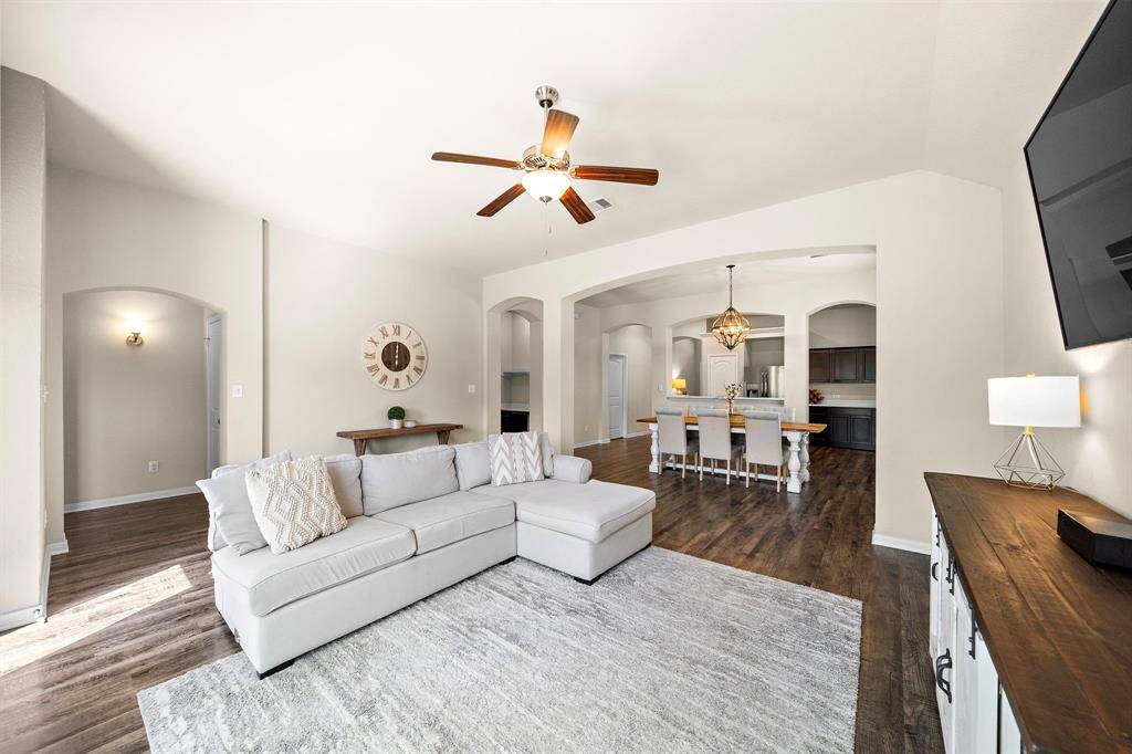 Expansive living area flows into the dining space and kitchen, showcasing an open-concept design that enhances both functionality and style. Highlights include wood-look flooring, elegant arched doorways, and a versatile study nook ideal for work or leisure.