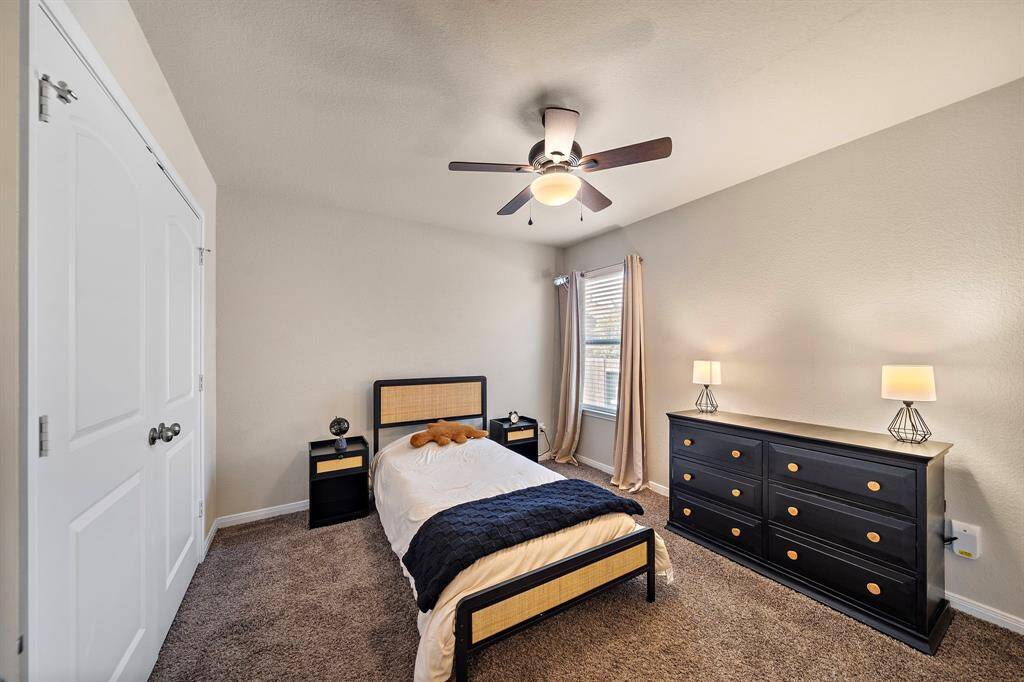 Secondary bedroom provides plush carpeting, a sizable window for abundant natural light, and a ceiling fan for year-round comfort.