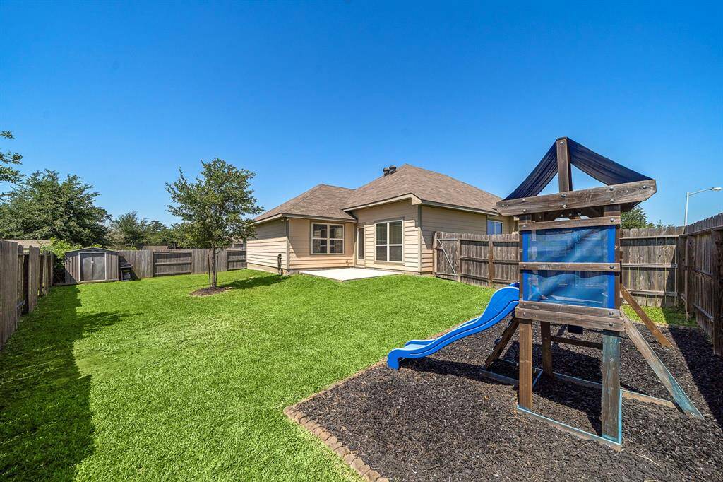 Spacious backyard features a dedicated playset with a slide, a handy storage shed, and an extended patio for outdoor dining or lounging. Located on a corner lot, this fully fenced yard offers privacy and abundant green space for recreation or gardening.
