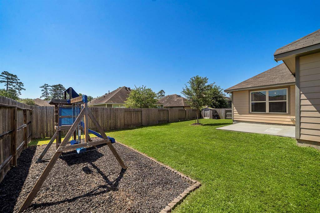 Generous backyard offers a dedicated playset on mulch, fully fenced perimeter, and abundant green space for outdoor recreation, gardening, or relaxing afternoons. The corner lot location provides additional privacy, with a convenient storage shed and cozy patio for lounging or weekend barbecues.