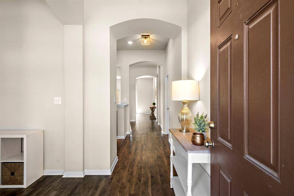 Inviting entryway welcomes you with elegant arched doorways and rich wood-look flooring spanning the length of the hallway. Thoughtfully placed accent lighting and a versatile console ensure a polished first impression, while the open sight lines set a bright, airy tone for the home’s interior.