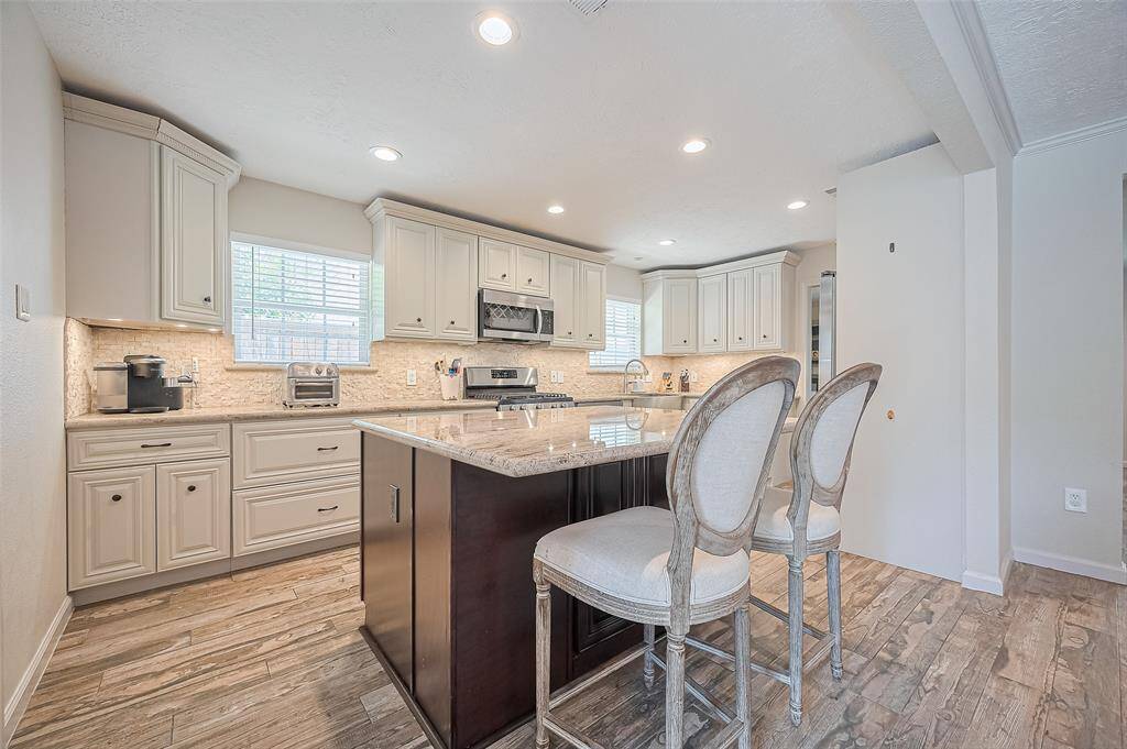This kitchen features elegant cream cabinetry, modern stainless steel appliances, and a spacious granite island with bar seating.