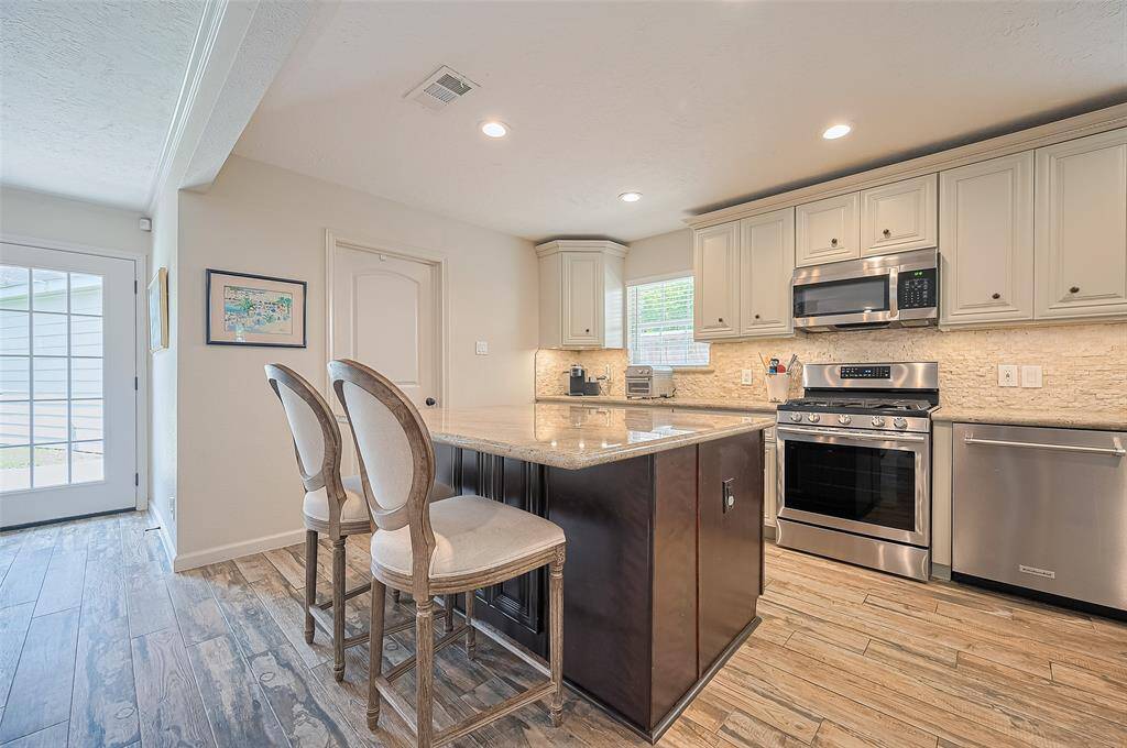 Every angle of this kitchen highlights its standout features—including a spacious eat-in island with storage on both sides, stainless steel appliances, and a centrally located gas range and oven.