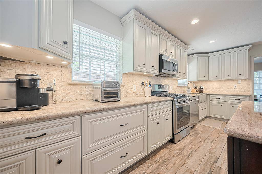 The kitchen is brightened by natural light streaming through two windows above the countertop.