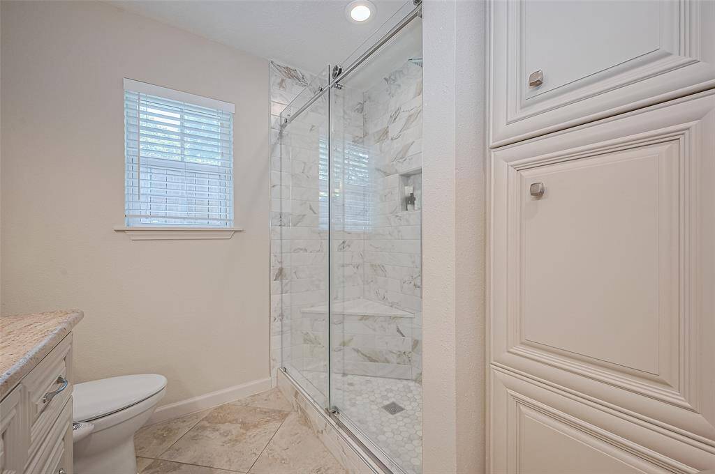 The walk-in shower is a true oasis, featuring a built-in bench and shelf, elegant tilework, and plenty of space to unwind.