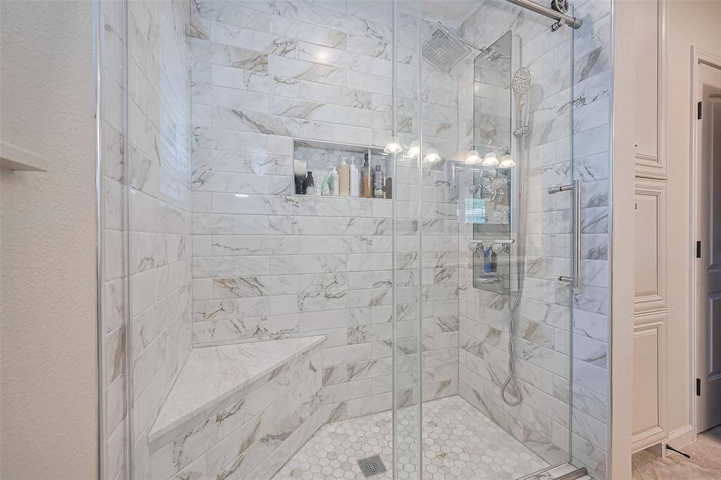 Here’s a closer look at the luxurious walk-in shower—your personal retreat. Beautifully finished with elegant tilework, it features a built-in bench and shelf for convenience, and is enclosed with sleek glass sliding doors that add a modern, polished touch to this spa-like space.