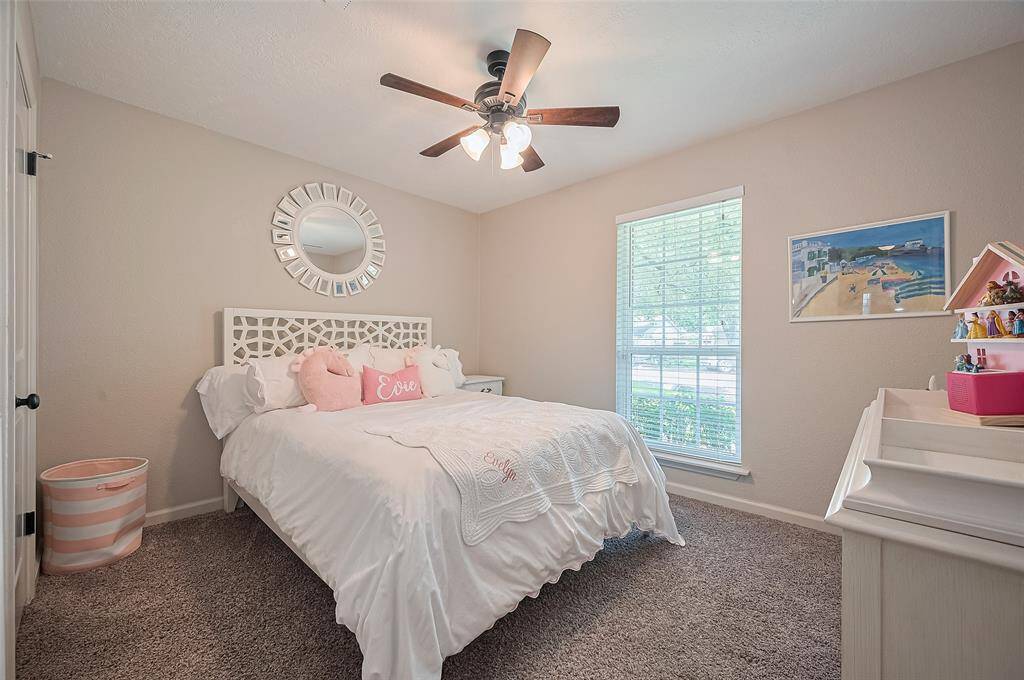 The front secondary bedroom features a ceiling fan with light fixture and two large windows that fill the space with natural light, creating a bright and airy atmosphere.