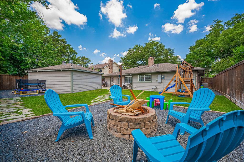 An alternate view from the corner of the yard captures the full scope of this inviting outdoor space—lush lawn, stone paths, spacious patio, play area, and plenty of room to relax or entertain, all framed by the charming backdrop of the home.